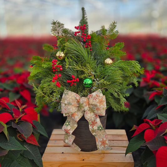 Decorative floral arrangement with a large bow on a wooden stand, surrounded by poinsettias.