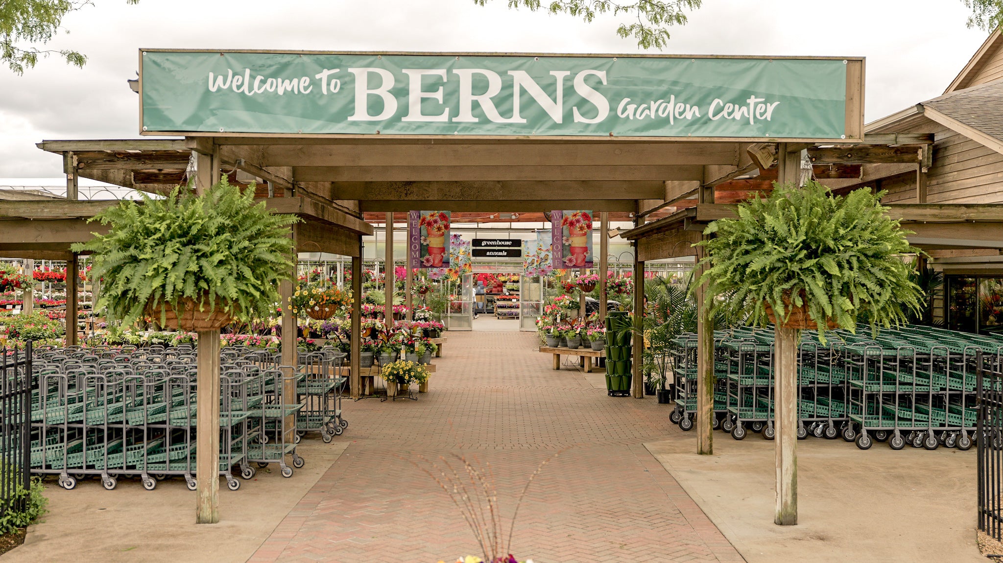 Entrance to Berns Garden Center with shoppers and garden supplies.