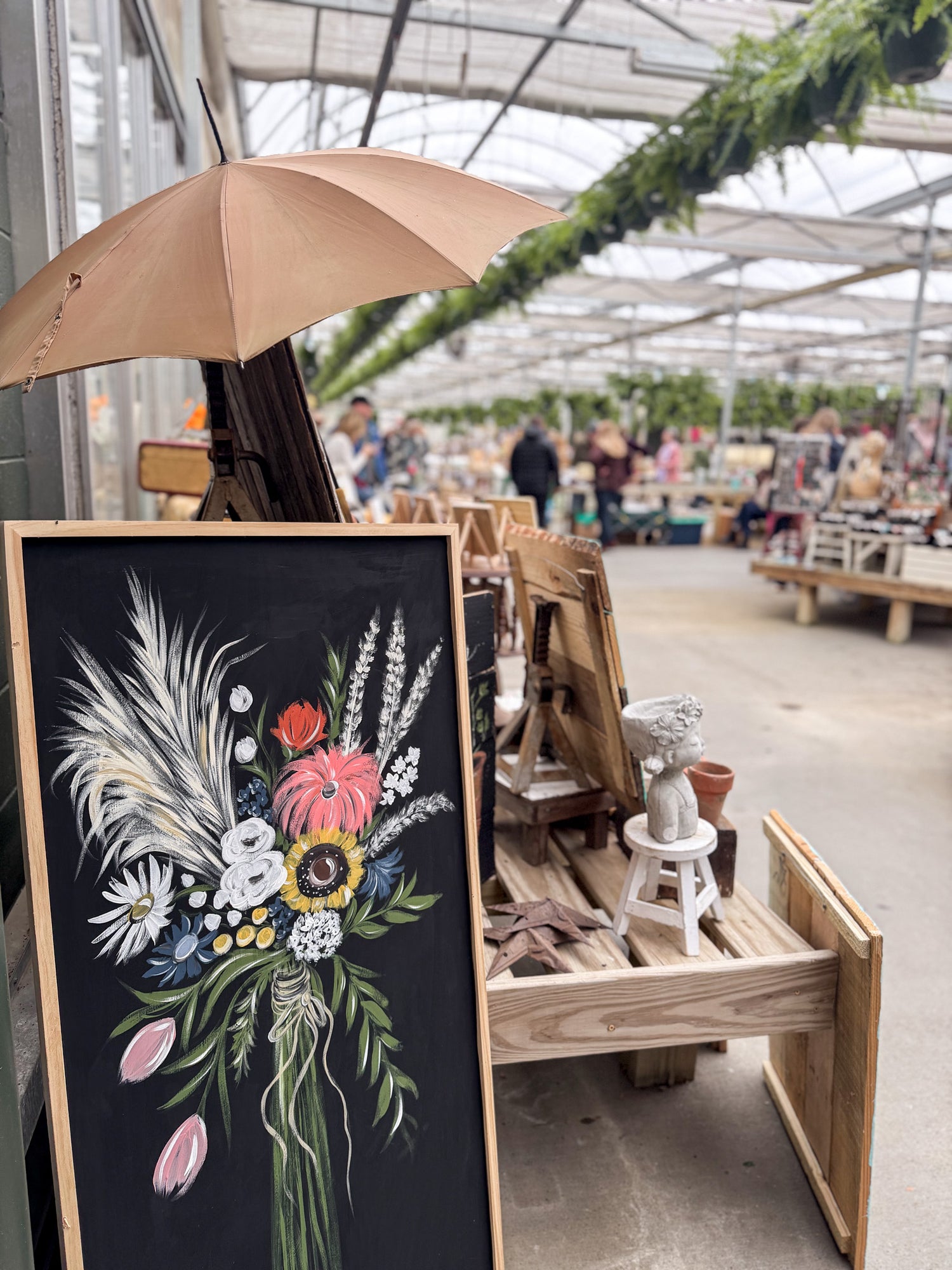Floral chalkboard art in a market setting with an umbrella and various items.